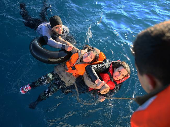 Getty Images Year in Focus 2016: Turkish Coast Guard personnel help refugees as they swim with buoys, after they toppled over a fishermen dinghy en route to Greece on January 22, 2016 in Didim district of Aydin, Turkey. 4 refugees body including 3 children pulled out of the water as Turkish coast guard personnel rescued 43 others. Photo by Emin Menguarslan/Anadolu Agency/Getty Images