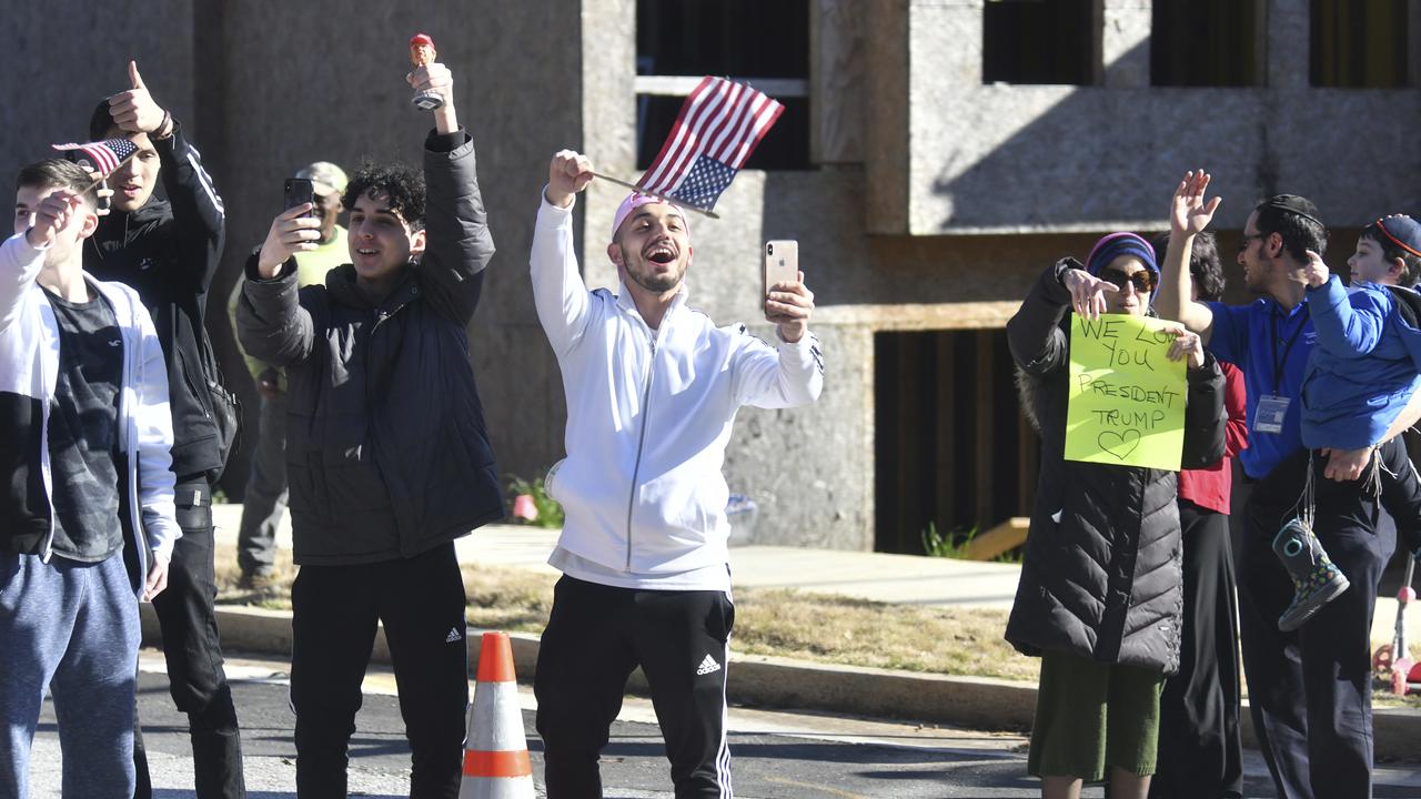 Supporters hold sings as the motorcade of President Donald Trump heads the headquarters of the Centers for Disease Control and Prevention in Atlanta on Friday. Picture: Hyosub Shin/Atlanta Journal-Constitution via AP