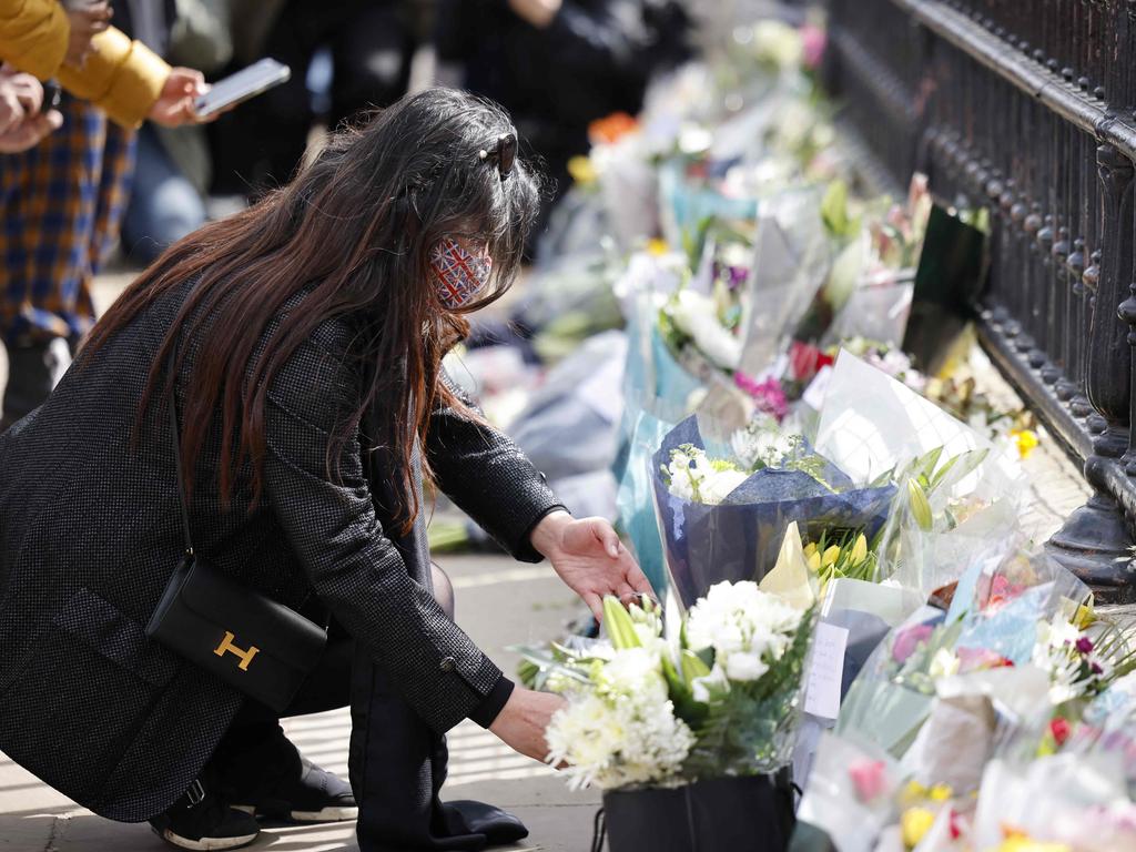 A woman adds a bunch of flowers to a line of floral tributes against the railings at the front of Buckingham Palace as crowds gathered to pay their respects. Picture Tolga Akmen / AFP)