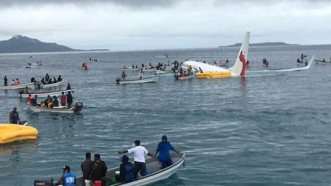 Locals in boats come to the aid of the stricken Air Niugini plane after it crashed into a lagoon. Picture Supplied