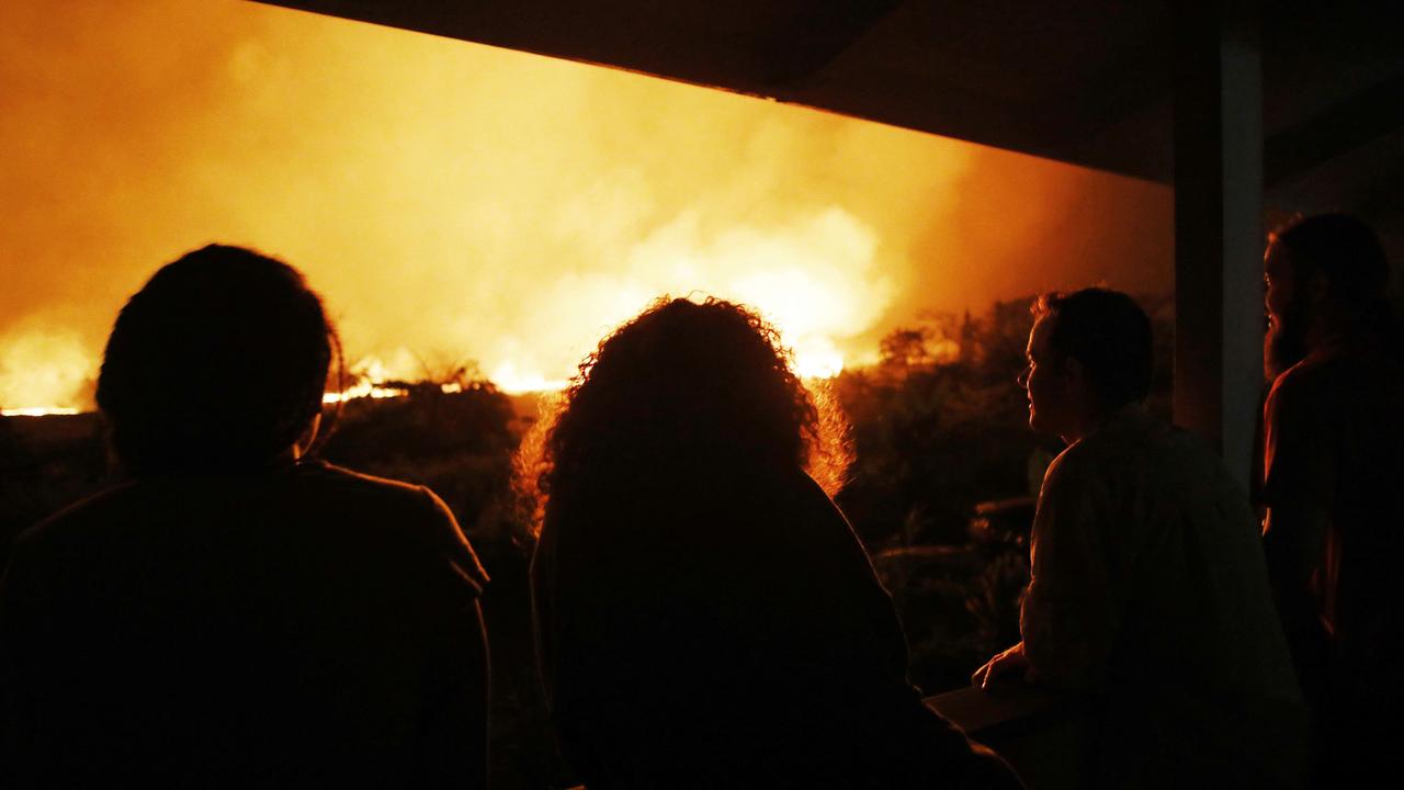 Residents view lava erupting from a Kilauea volcano fissure, at a small viewing party on a neighbor's porch, on Hawaii's Big Island on May 19, 2018 in Kapoho, Hawaii. Some local residents have held small viewing parties to view lava. Picture: Mario Tama/Getty Images/AFP