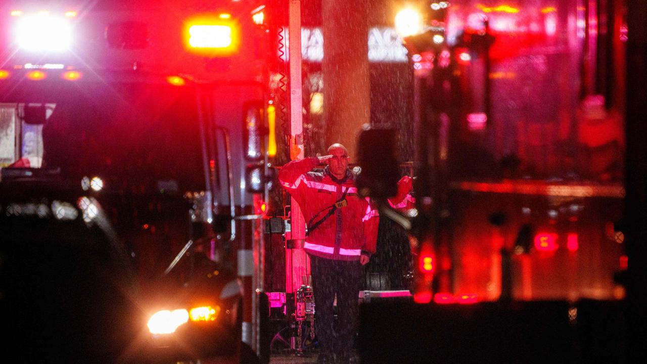 A first responder salutes as two ambulances carrying the flag draped bodies of service members killed.