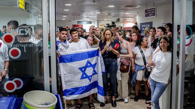 A man holds an Israeli flag as people gather inside the medical centre where the four Israeli hostages were transferred. Picture: AFP