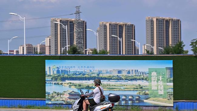 A motorist rides past a billboard and residential towers in Beijing. Picture: Adek Berry/AFP