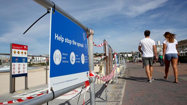 Locals walk along the esplanade at Bondi where the beach is closed due to social distancing measures put in place because of the coronavirus. Picture: Toby Zerna