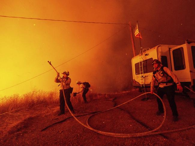 Firefighters spray water on the Hughes Fire in Castaic, Calif., Wednesday, Jan. 22, 2025. (AP Photo/Ethan Swope)