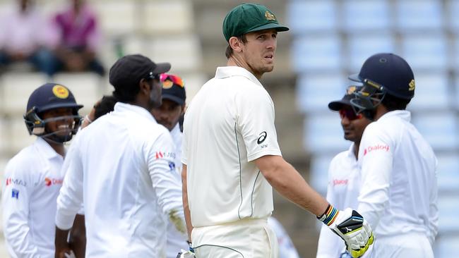 Australia's Mitchell Marsh (C) walks back to the pavilion after losing his wicket.