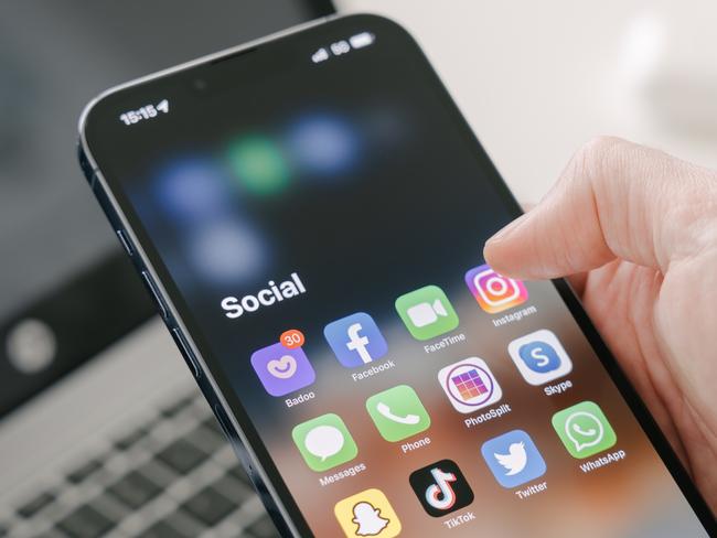 Gothenburg, Sweden - March 23, 2022: A man's hand holds a Iphone 13 Pro max with social media apps, against the background of a laptop. Blurred background. Selective focus. Picture: iStock