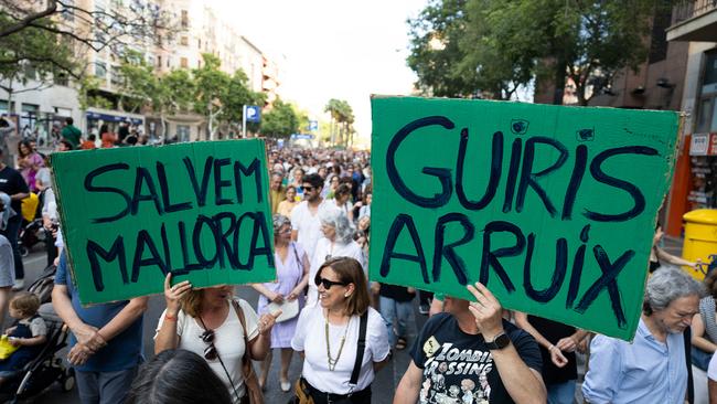 Protesters hold signs reading 'Let's save Mallorca' and 'Foreigners out'. 