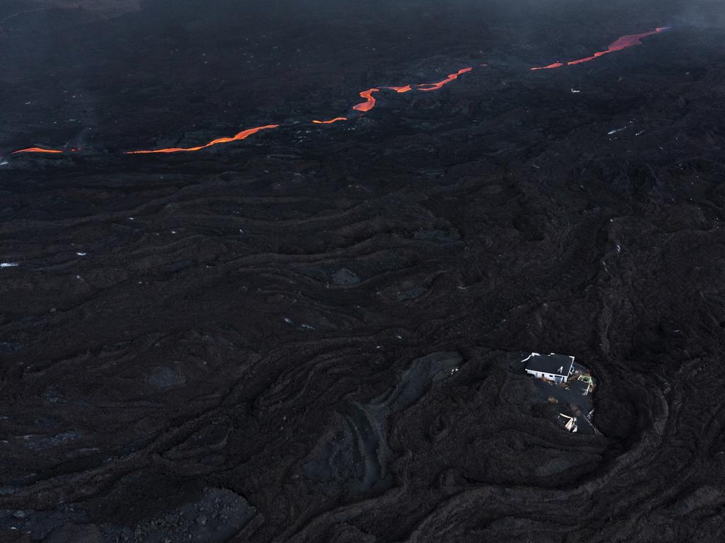Lava flows past buildings sitting under the Cumbre Vieja volcano. Picture: Dan Kitwood/Getty Images