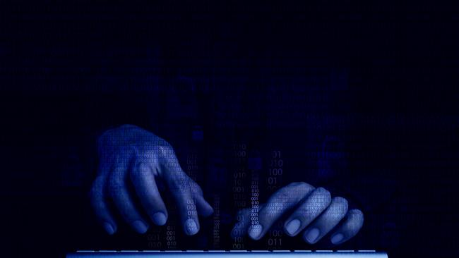 Cyberattack and internet crime, hacking and malware concepts. Digital binary code data numbers and secure lock icons on hacker' hands working with keyboard computer on dark blue tone background. Picture: iStock