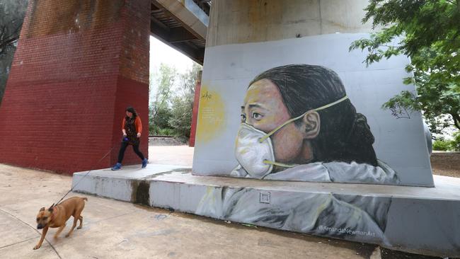 A dog walker goes past a Melbourne mural painted by artist Amanda Newman of Ai Fen, one of the first doctors to raise the alarm on COVID-19. Picture: Robert Cianflone/Getty Images