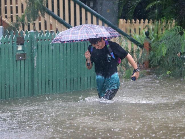 Rigby Wilshire wades through flood waters to get to his home in East Brisbane. Picture: Darren England.