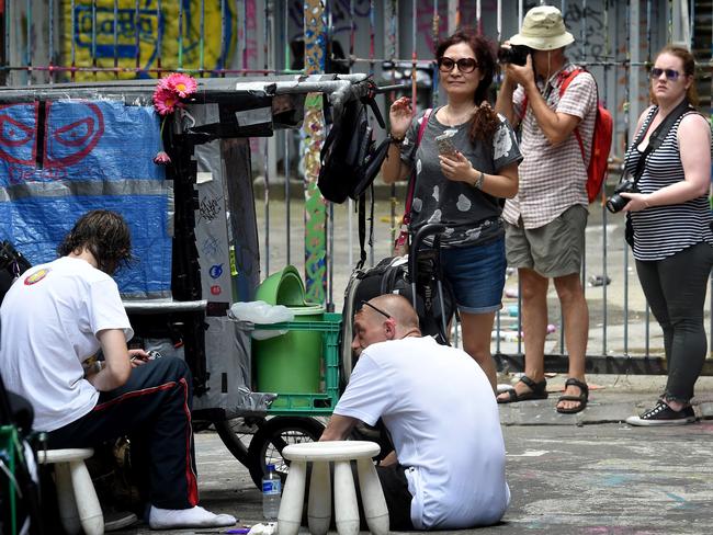 Tourists at Hosier Lane walk past genuinely homeless people loitering in the laneway. Picture: Nicole Garmston