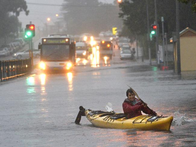 A woman paddles her kayak along Pittwater Road in Narrabeen as the floods continue to threaten homes. Picture: Jeremy Piper