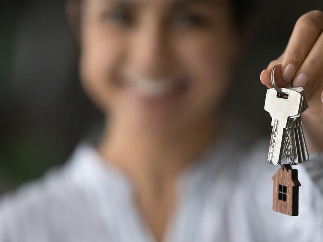 New home. Blurred portrait of smiling young female seller Real Estate Agent broker holding key in hand giving you client customer buyer renter after making successful deal. Soft focus on bunch of keys. Close up