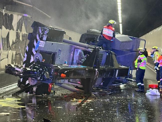 A major Sydney motorway has been closed in both directions after a crane rolled over on Tuesday morning, sending the roads into chaos and leaving one man in hospital. Both lanes on the M5 Motorway East Tunnel have been closed after a crane rolled over on its side about 11.30am Tuesday. Picture: Live Traffic NSW