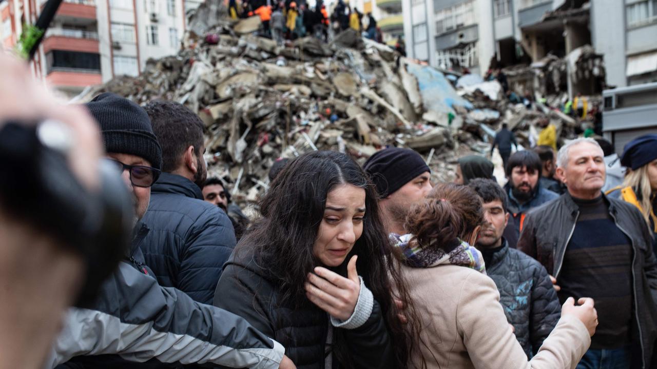 TOPSHOT - A woman reacts as rescuers search for survivors through the rubble of collapsed buildings in Adana, on February 6, 2023 after a 7,8 magnitude earthquake struck the country's south-east. - The combined death toll has risen to over 1,900 for Turkey and Syria after the region's strongest quake in nearly a century. Turkey's emergency services said at least 1,121 people died in the earthquake, with another 783 confirmed fatalities in Syria. (Photo by Can EROK / AFP)