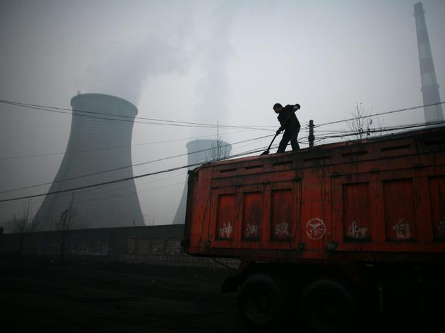 A truck driver shovels coal hear a coal-fired power plant in Linfen.