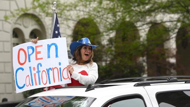 A woman holds out a sign calling for California to open as hundreds of people gather to protest the lockdown in spite of shelter-in-place rules still being in effect at California's state capitol building in Sacramento. Picture: AFP.