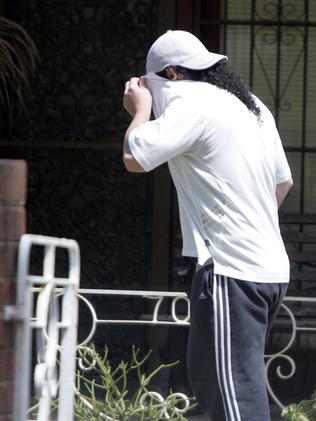 Sharrouf (left) covers his face at his home in Punchbowl, Sydney, in 2011. Picture: Jess Husband.