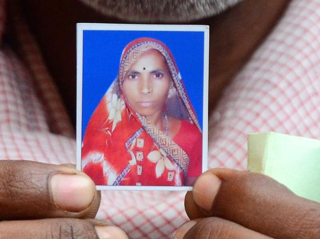 Indian villager Roop Chand Srivastava, the widower of Phool Bai Srivastava who died after undergoing a mass sterilisation operation in a government-run programme, holds a portrait of his late wide outside their residence in Amsena village, about 20 kms from Bilaspur on November 15, 2014. India has defended a state-run programme that offers poor women cash incentives to get sterilised after the deaths of 13 women triggered international condemnation. AFP PHOTO/SANJAY KANOJIA