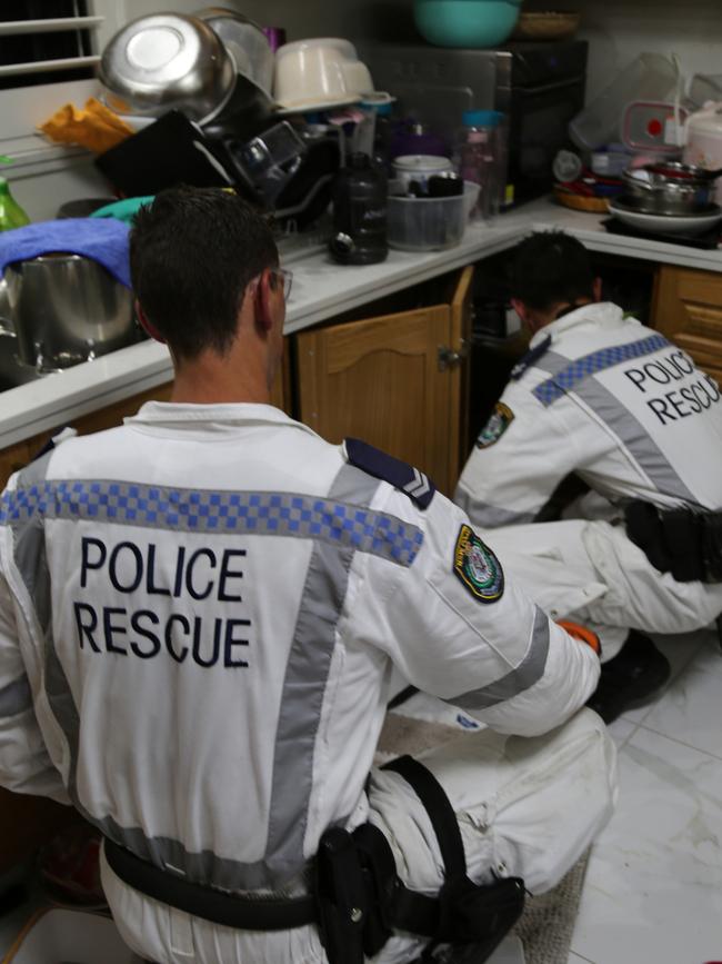 Police checking the kitchen cupboards where the alleged money was found. Picture: NSW Police