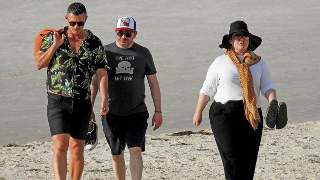 US actor Melissa McCarthy out for a beach walk in Byron Bay with her actor husband Ben Falcone (cap) and actor Luke Evans. Picture: Nathan Edwards