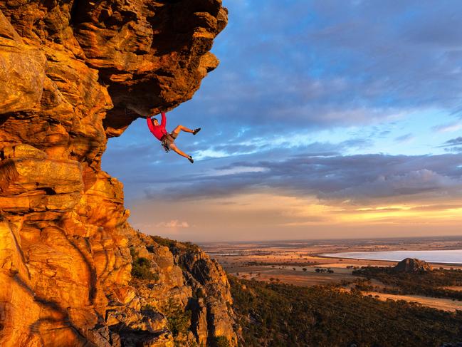 Free climber Tom Perkins swings out on Feeling the Ceiling, a grade 21 climb near the summit of Mount Arapiles at first light. Picture: Jason Edwards