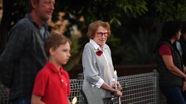 90 year-old Kathleen Callaghan is joined by neighbours as she stands outside her home at dawn to commemorate Anzac Day in Brisbane, Saturday, April 25, 2019. Anzac Day is a national day of remembrance to commemorate the service and sacrifice of Australian and New Zealand service men and women. Due to COVID-19 restrictions marches and commemorative services have been banned for the first time in more than a century. (AAP Image/Dan Peled) NO ARCHIVING
