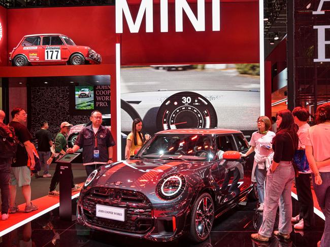 People stand next to a Mini John Cooper Works displayed during the 21st Shanghai International Automobile Industry Exhibition at the National Exhibition and Convention Center in Shanghai on April 27, 2025. (Photo by HECTOR RETAMAL / AFP)
