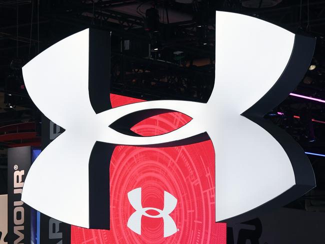 (FILES) This file photo taken on January 04, 2017 shows attendees walking by the Under Armour booth at CES 2017 at the Sands Expo and Convention Center in Las Vegas, Nevada.  Shares of Under Armour stumbled early October 31, 2017 after the athletic apparel and shoe maker slashed its full-year profit forecast following weak quarterly earnings caused by falling sales in North America. Near 1440 GMT, Under Armour had dropped 13.0 percent at $12.82.The brand, which pitches itself as a rival to Nike and Adidas, was on the upswing a couple of years ago, boosted by high-profile sponsorships of basketball star Stephen Curry, champion golfer Jordan Spieth and other prominent athletes.  / AFP PHOTO / GETTY IMAGES NORTH AMERICA / Ethan Miller