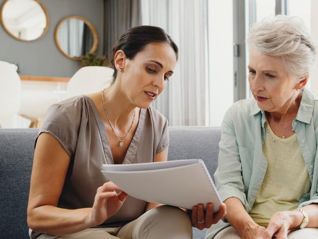 Caregiver talking to senior woman about insurance, support with finance documents and help reading retirement paperwork on the sofa in home. Girl helping elderly person with Alzheimer care at house