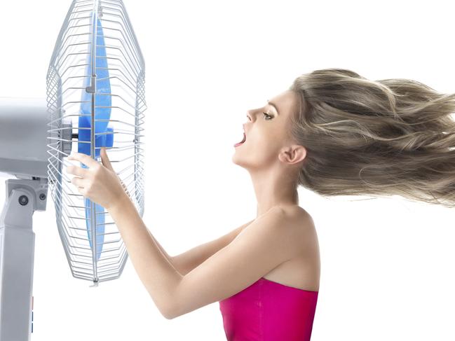 A young woman cooling her face with a fan. Picture: iStock.