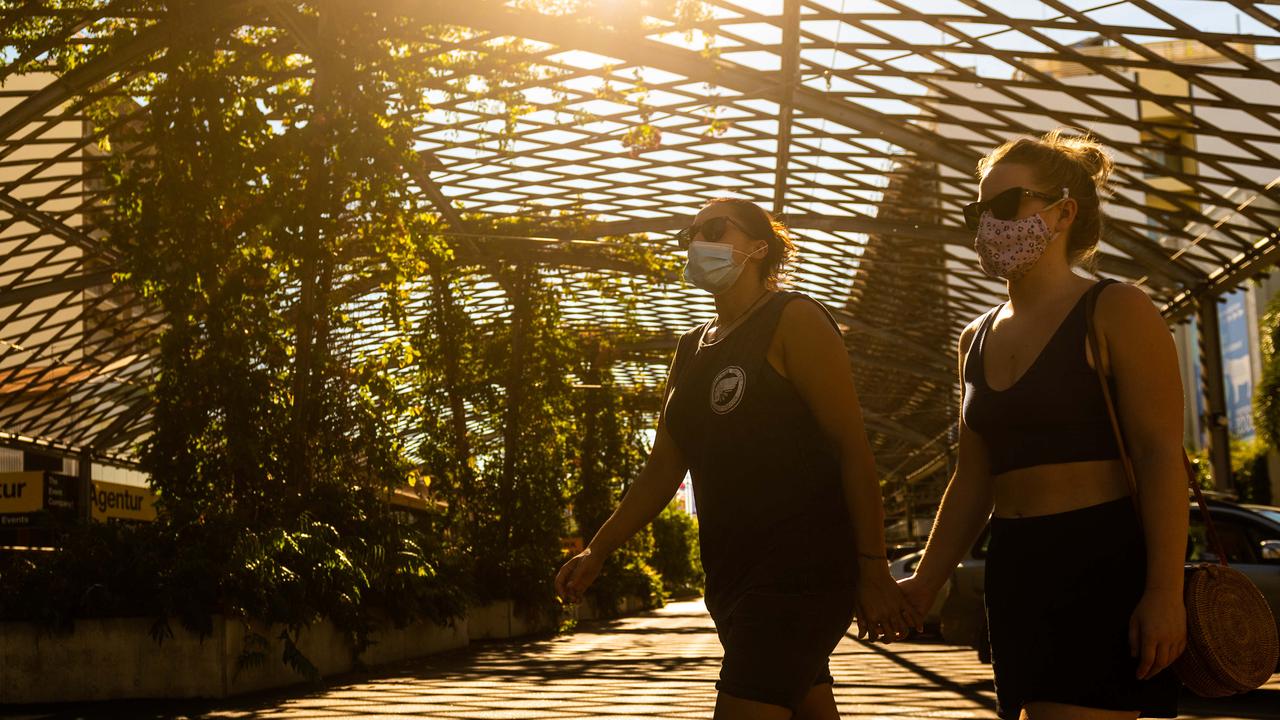 A couple walk under the Cavenagh St shade structure in Darwin’s afternoon light on the third day of the lockdown. Picture: Che Chorley