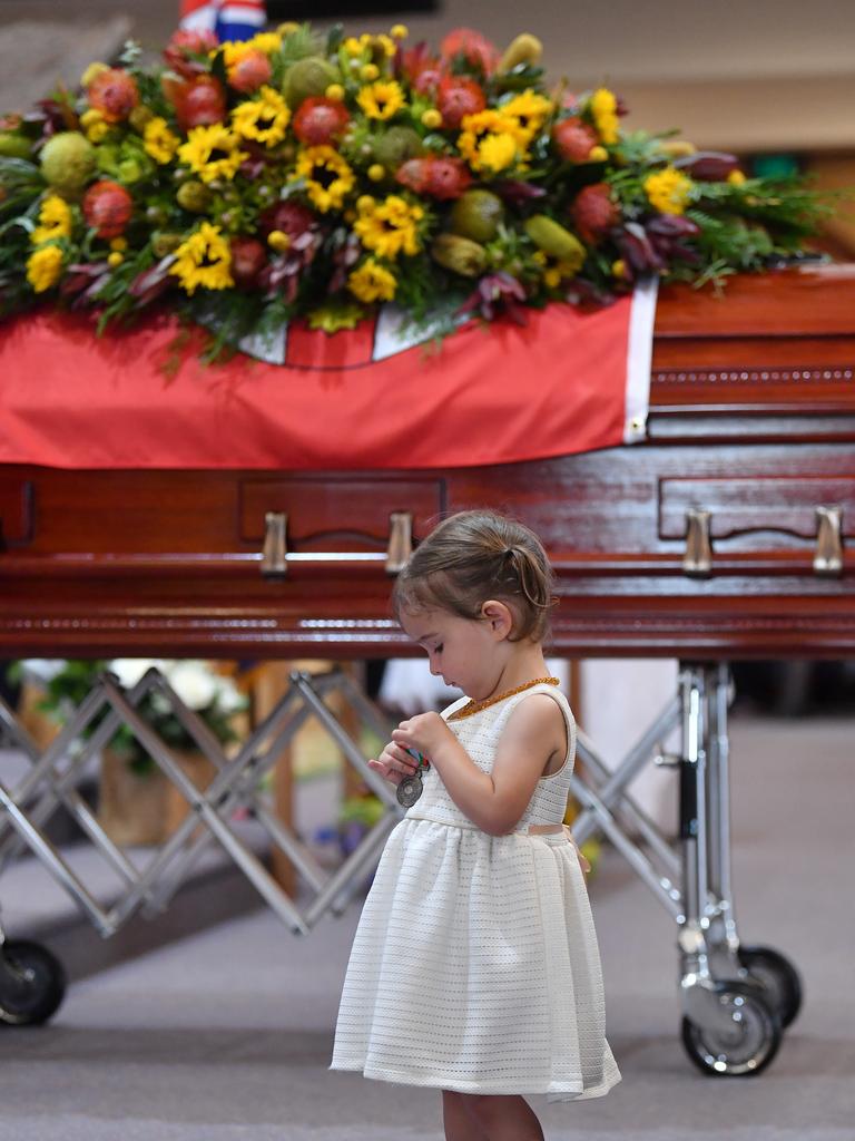 Charlotte O'Dwyer, the young daughter of Rural Fire Service volunteer Andrew O'Dwyer stands in front of her fathers casket as she looks at the service medal presented to her by RFS Commissioner Shane Fitzsimmons. Picture: Dean Lewins/Getty Images