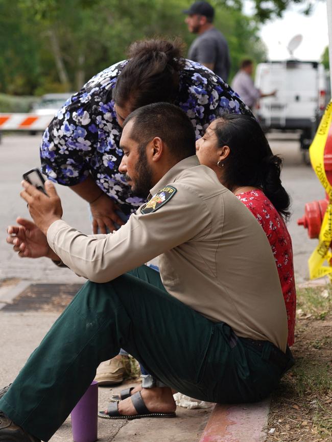 A sheriff checks his phone as he sits on the sidewalk outside the Texas school. Picture: Allison dinner / AFP