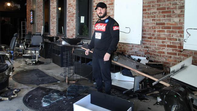 Johnny Slicks barber shop owner MJ Casalbore assesses the extent of damage inside his shop. Picture: Dean Martin