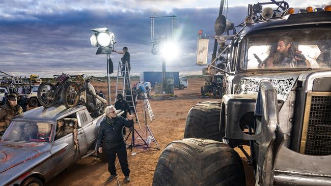 Anya Taylor-Joy (in car) and Chris Hemsworth (inside truck) flank George Miller on the set of Furiosa Picture: Jasin Boland/Warner Bros