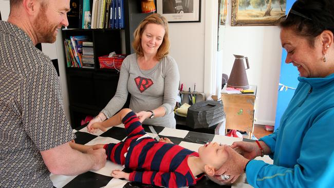 David andd Ina Mills give son Roki, 3, physiotherapy at their Newport home, with the help of volunteer Candice West. Picture: Troy Snook