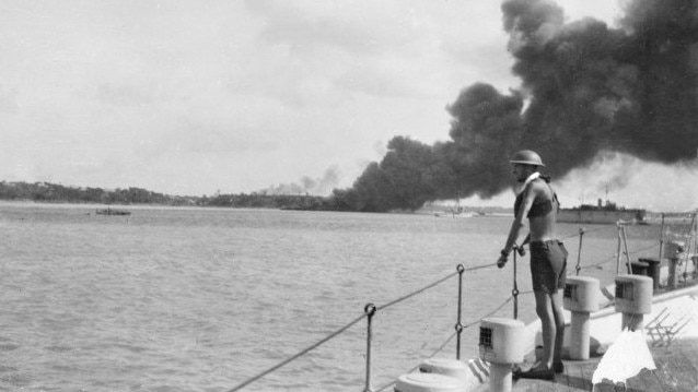 An unidentified sailor on board HMAS Platypus watches smoke bollowing from MV Neptuna after she was destroyed during the first Japanese air raid on Darwin. Picture: Australian War Memorial.