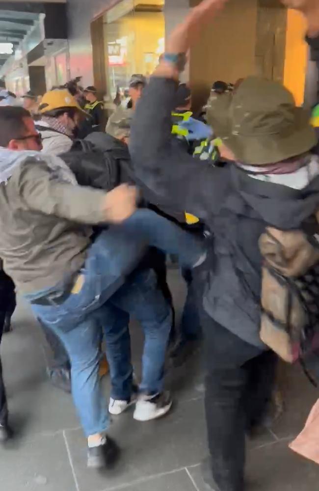 A man is seen kicking a police officer on Bourke St. picture : Fergus Ellis