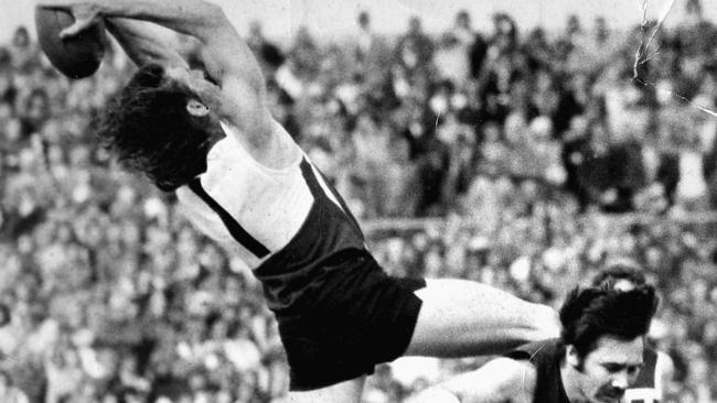 Port Adelaide's four-time Magarey Medallist Russell Ebert flies high over Glenelg’s Peter Marker.