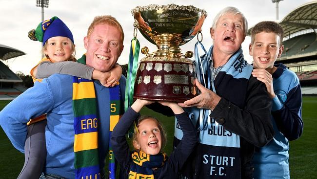 GRAND PLANS: Gavin Colville, who captained Woodville-West Torrens for six years from 2001, and football legend Paul Bagshaw will deliver the Thomas Seymour Hill Cup to Adelaide Oval for Sunday’s SANFL Grand Final clash between the Eagles and Sturt. Colville is pictured with daughters Madison and Lily, while Bagshaw is with grandson Rhys Carey. Picture: Tricia Watkinson