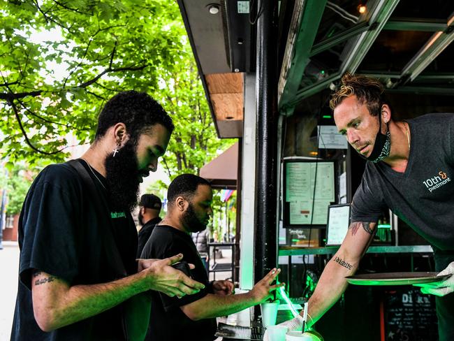 Bar tender Jake Glazier (34) (R) serves his customers at an open roadside bar in Atlanta, Georgia, on April 23, 2020. - The US state of Georgia takes a massive gamble on April 24 when it allows businesses like gyms and hair salons to re-open to ease a painful coronavirus lockdown, a move even President Donald Trump fears is too soon. "It's good for my pay check, you know, I make obviously all my money here on tips and so the more people I see per day the more money I make. Thankfully I've been able to do takeout and still make a little bit of tip money, but you know, it's good to be open for me, financially," Glazier said. (Photo by CHANDAN KHANNA / AFP)