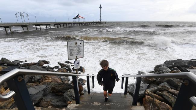 A boy outruns a wave as high tide surges at Brighton Jetty on Thursday. Picture: AAP / Mark Brake