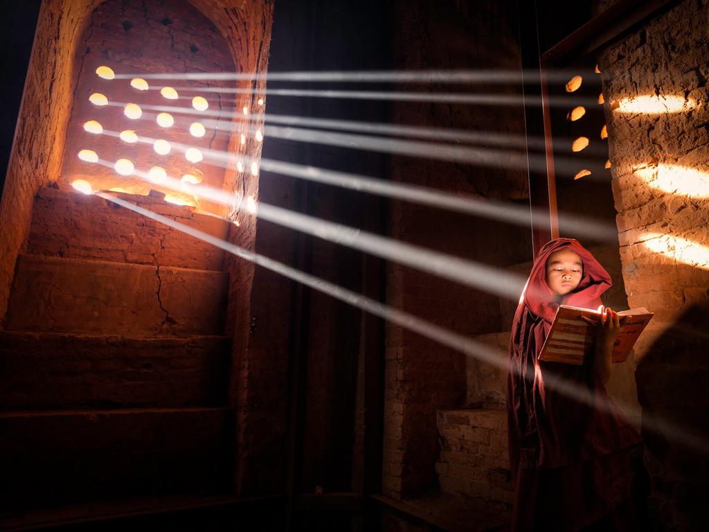 “LightSource” by Marcelo Castro / National Geographic Traveler Photo Contest Young Monk finds a perfect light source to read his book inside of his pagoda — Old Bagan, Myanmar Location: Old Bagan. Picture: <a href="http://travel.nationalgeographic.com/travel/traveler-magazine/photo-contest/2014" target="_blank">National Geographic Photo Contest </a>