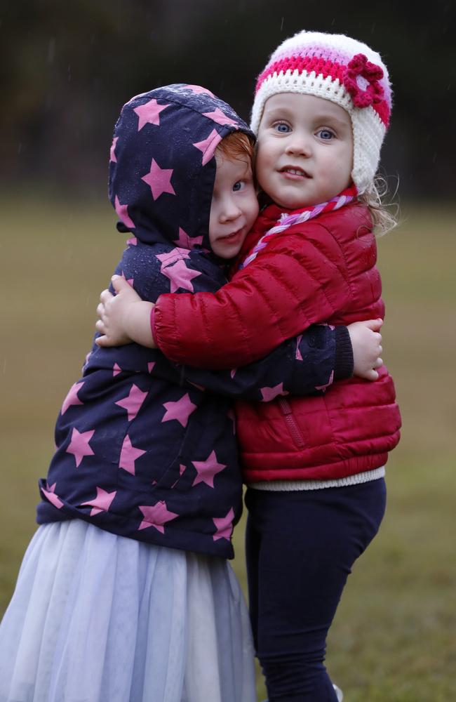 Two-year-old friends Arun (left) and Abigail hug to keep warm in Centennial Park on Thursday. Picture: Jonathan Ng