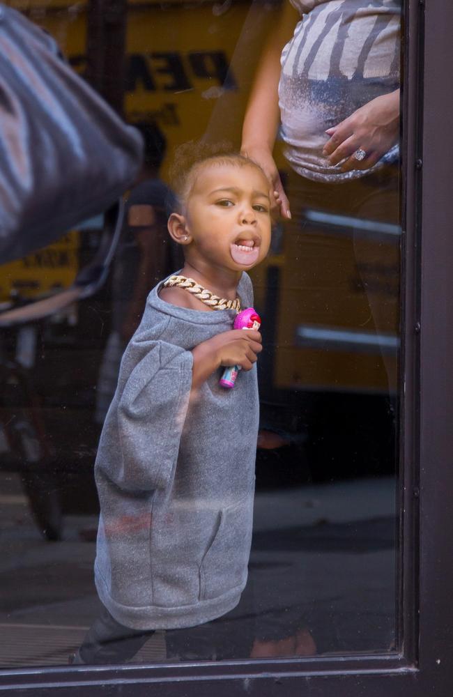 Cheeky North West makes faces through the glass door at Milk Studios. Picture: Splash