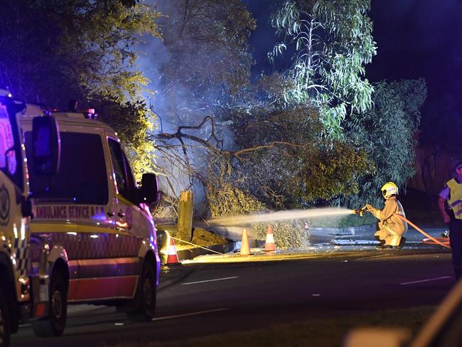 A firefighter hoses down the flaming car. Picture: Gordon McComiskie